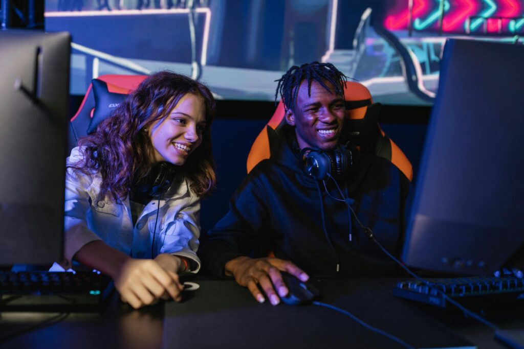 Multiracial friends gaming with computers and headphones, enjoying esports indoors.