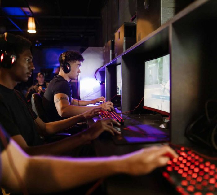 Young adults gaming at a modern LAN center with advanced PCs, showcasing intense gaming focus.