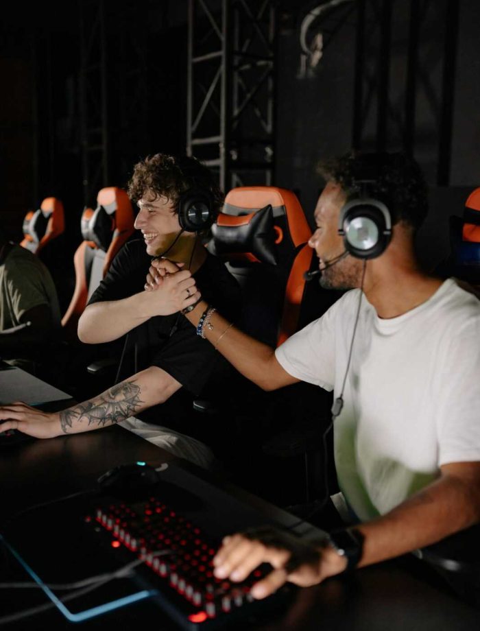 Two excited gamers shake hands, celebrating a win on their gaming setup indoors.