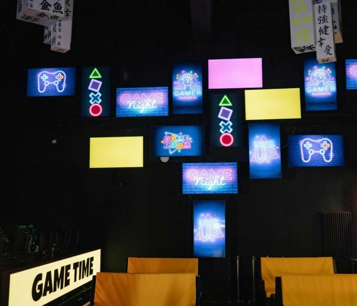 A lively gaming room displaying bright neon signs and screens, creating an immersive atmosphere.
