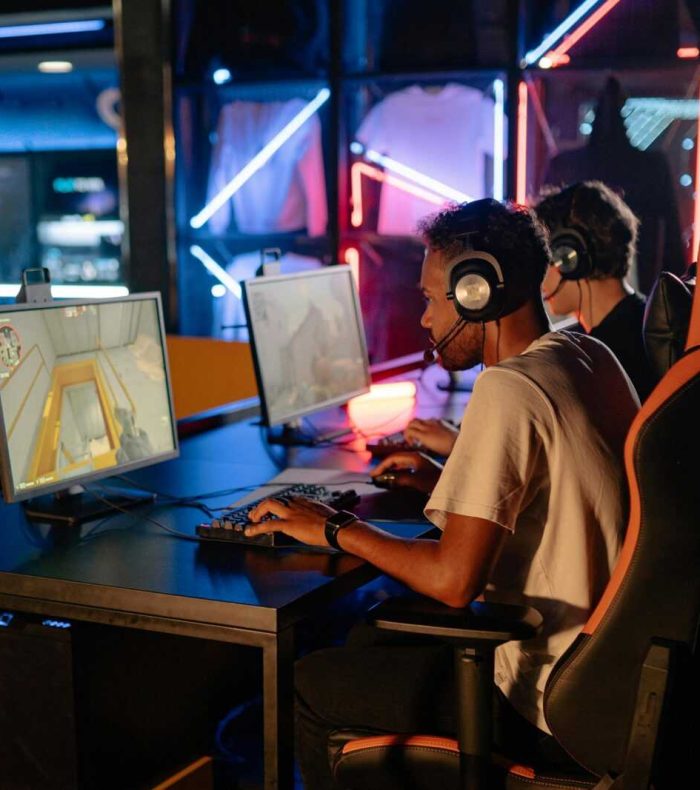 Competitive gaming session with friends indoors featuring high-tech computers and neon lights.